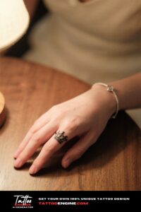 A woman's hand with a crown tattoo resting on a wooden table.