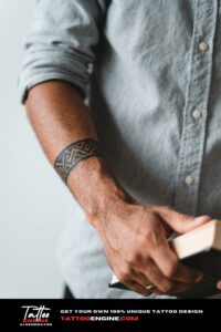 Close-up of a man's wrist with a geometric tribal tattoo holding a book