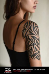 A woman's back and shoulder showing a bold black ink tribal tattoo, with a softly blurred backdrop.