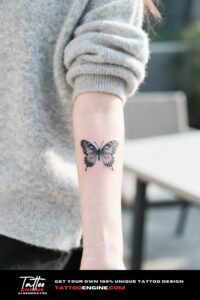 A close-up of a detailed butterfly tattoo on a woman's forearm with a gray sweater