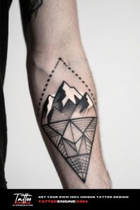 Close-up of a man's forearm with a geometric mountain tattoo in a navy blue sweater.