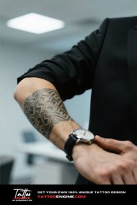Close-up of a man's forearm with a geometric tattoo, adjusting a watch in a black suit.