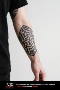 Extreme close-up of a man's forearm with a labyrinthine geometric tattoo in a grey t-shirt.