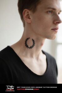 Close-up of a fine-line laurel wreath tattoo on a man's collarbone with a black t-shirt.