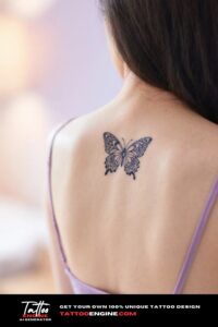 A close-up of a mandala-style butterfly tattoo on a woman's back with a lavender top