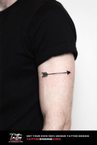 Close-up of a man's forearm with a minimalist arrow tattoo in a light grey shirt.