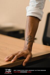Close-up of a man's wrist with a tree tattoo, wearing a white shirt.