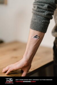 Close-up of a minimalist wave tattoo on a man's wrist with a charcoal grey sweater.
