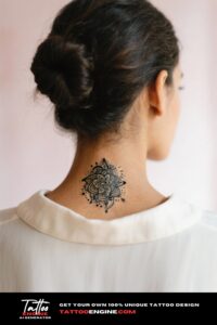 A close-up of a woman's nape with a mandala tattoo, hair in a bun.