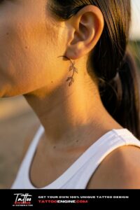 Fine-line crescent moon with floral stem tattoo behind the ear on caramel skin, golden light.