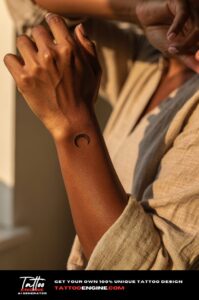 Healed crescent moon tattoo on a woman’s outer wrist, black ink, natural skin texture visible.