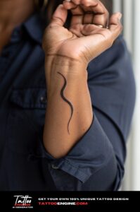 Simple black wave line tattoo on inner wrist, medium-brown skin, navy shirt, soft daylight.