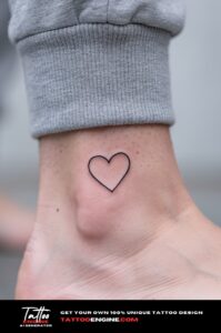 Small black line heart tattoo on a woman&rsquo;s inner ankle, crisp and fully healed.