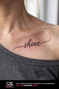 Healed script tattoo "shine" on a woman's collarbone, charcoal t-shirt neckline stretched wide.