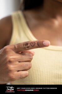Tiny ultra-fine heart outline tattoo on inside of index finger, neat and subtle.